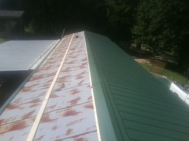 Old rusted panels beside newly installed green metal roofing — Wind Damage Roof Repair by Roofing Brothers in Gooding