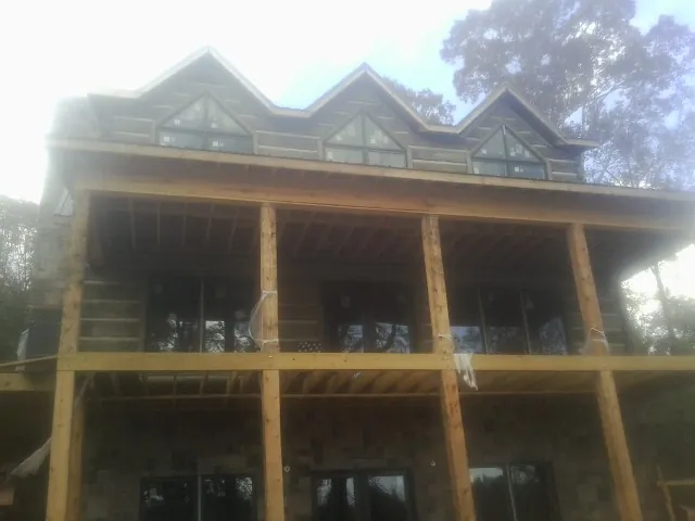Dormers and porch framing on a large log home under construction — Roof Coating work by our crew in Gooding