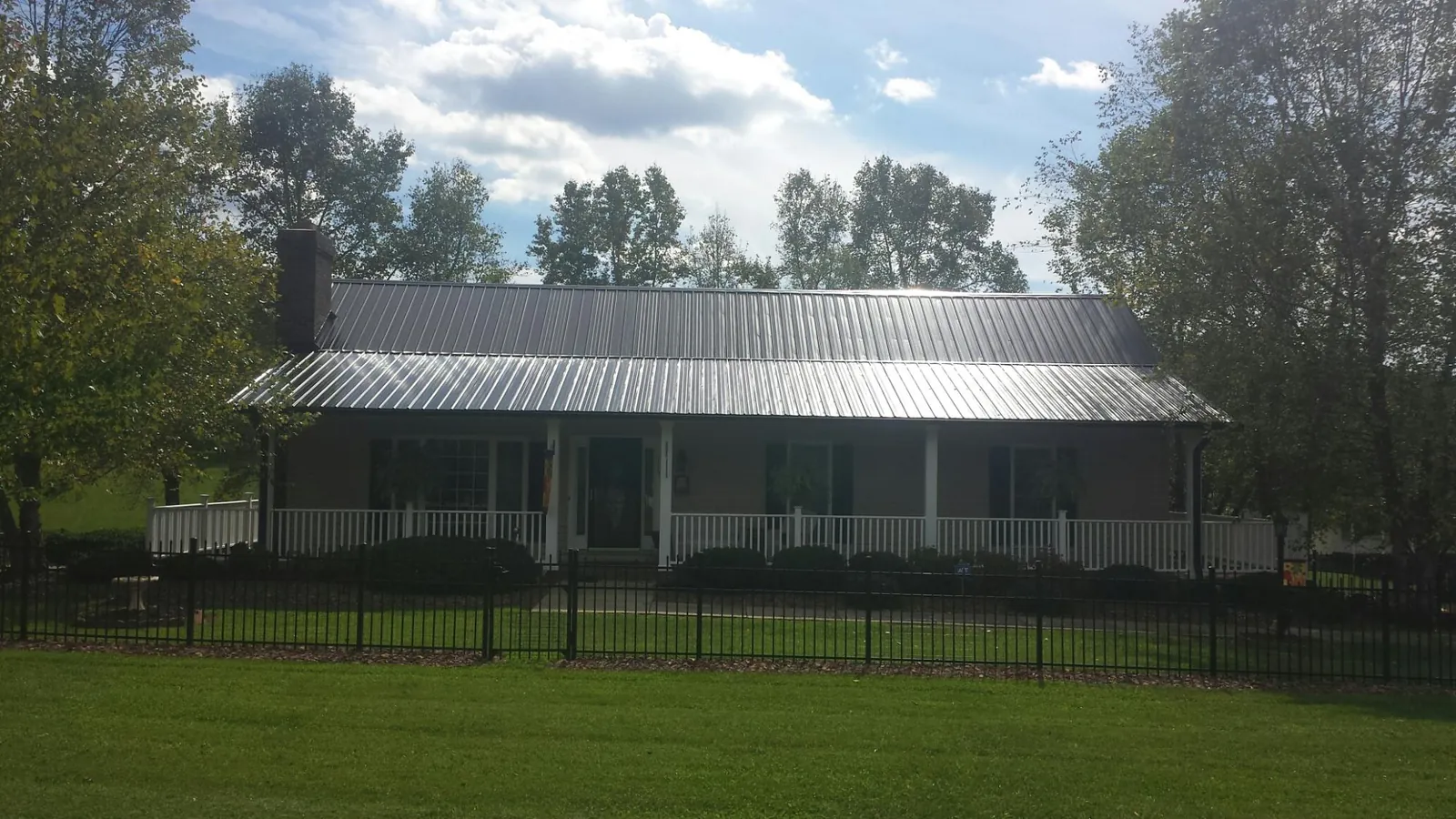 Gray metal roof on a brick ranch with a full width front porch — Gutter Guard Installation work by our crew in Gooding